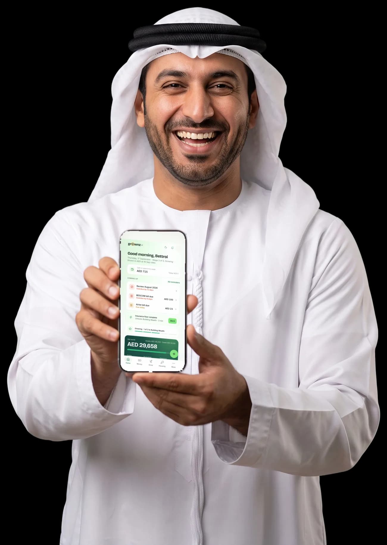 A man in a white kandura laughing and holding his phone up to the camera, the Grownz home screen showing