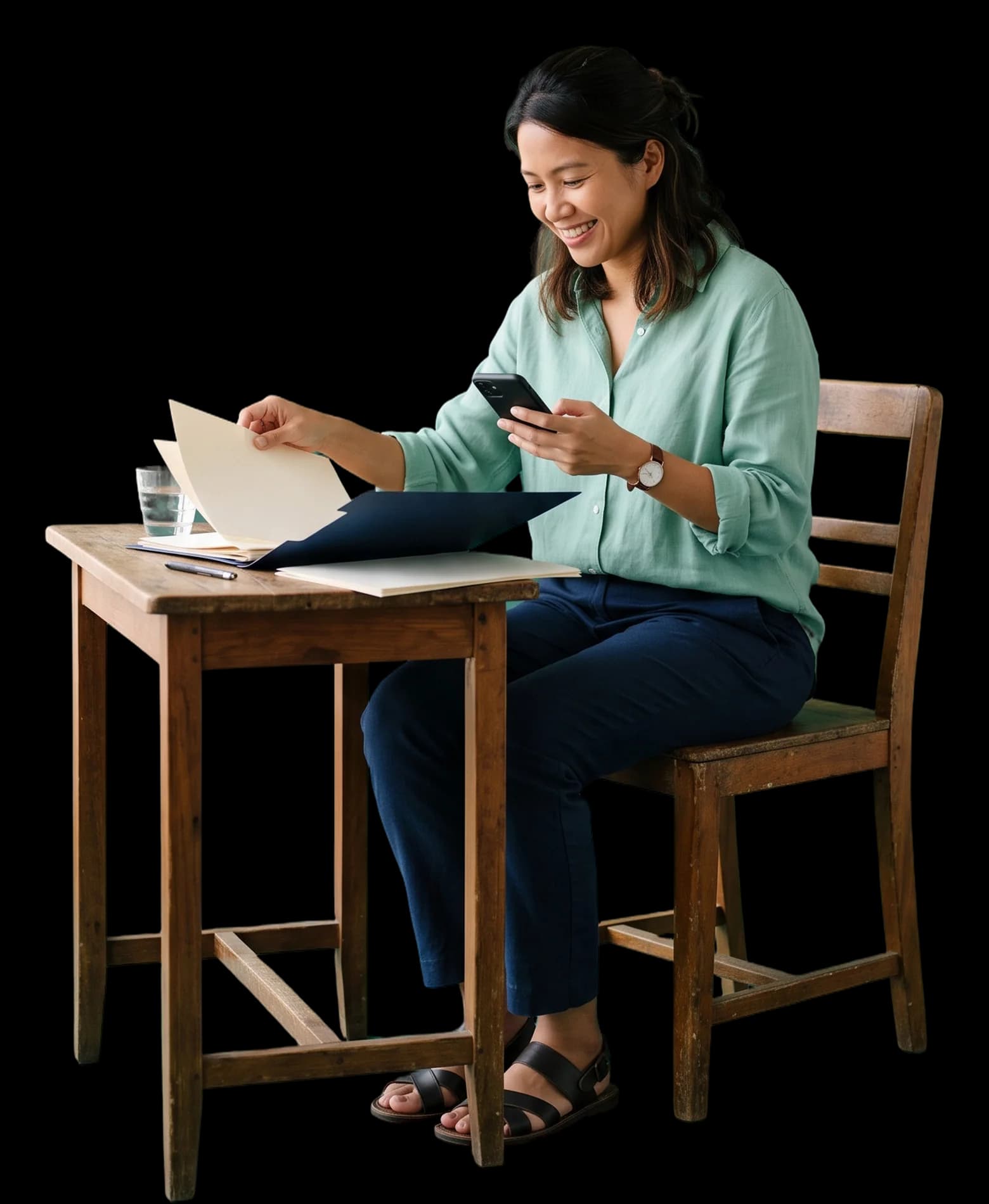 A woman sorting bills into a folder while checking her phone