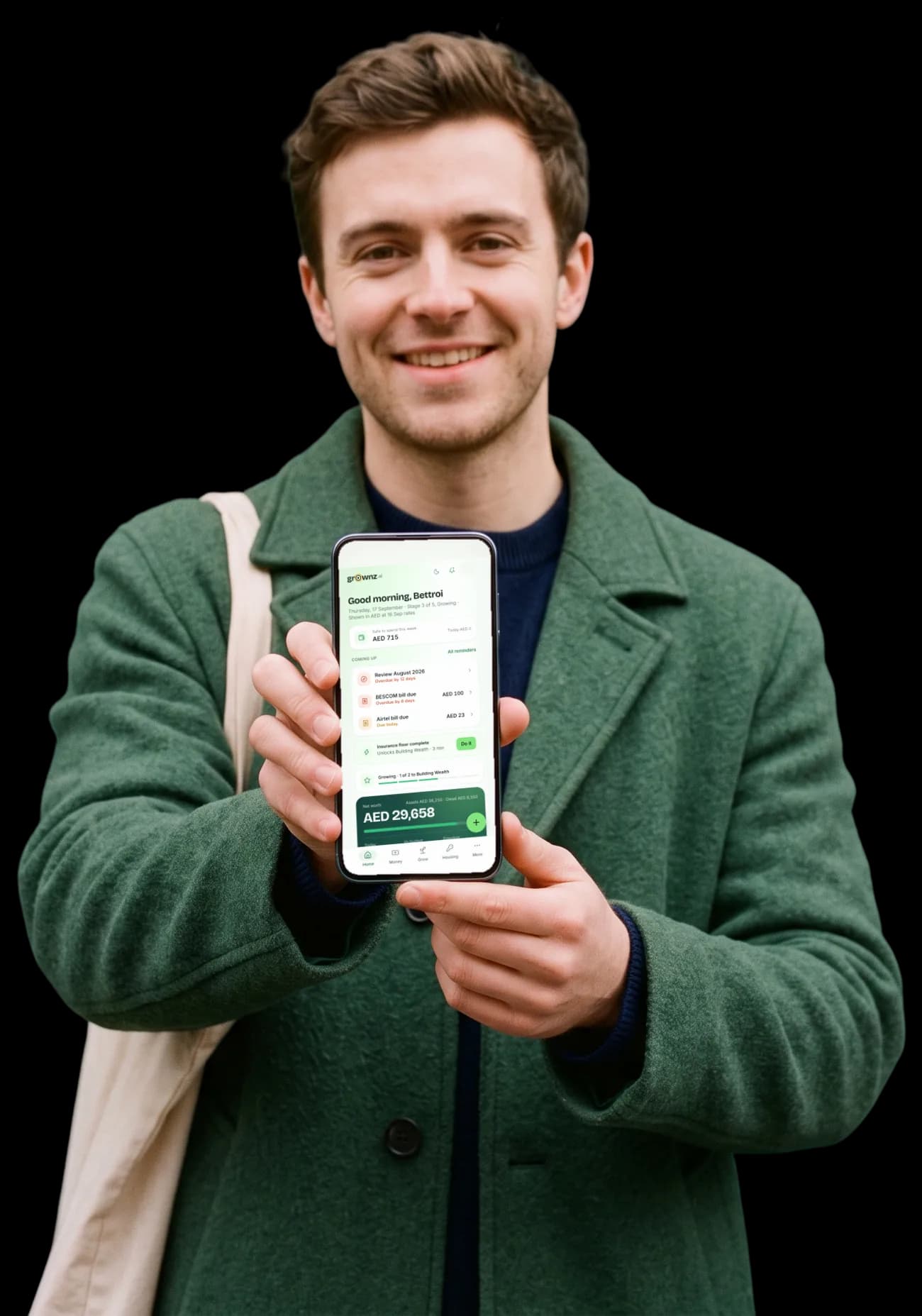 A man in a green wool coat holding his phone up to the camera, the Grownz home screen showing